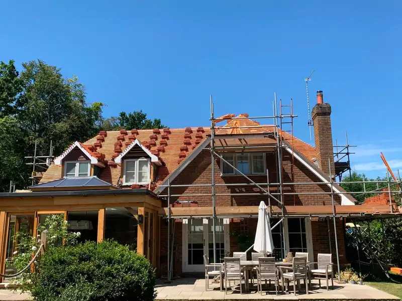 New clay tiled roof being installed on a large scaffolded family home